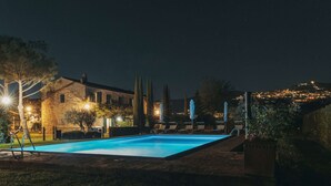 Une piscine entourée de bâtiments en pierre, avec une vue sur le paysage urbain en arrière-plan.