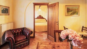Une pièce chaleureuse avec un plafond en bois, un canapé en cuir, une table à manger en bois agrémentée d’un vase de fleurs et un lit avec une tête de lit en bois.