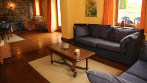 A cozy living room with a dark blue sofa, wooden coffee table, and a stone wall.
