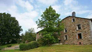A stone building with a grassy lawn and trees.