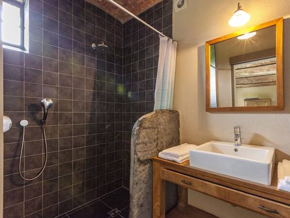 A bathroom with a shower, a sink, and a mirror.