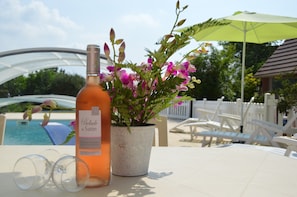A bottle of wine, a potted plant, and a poolside setting with lounge chairs and a white fence. - Holiday Home Folleville Near Asterix Park (Folleville)