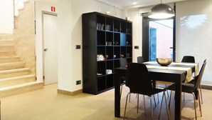 Ett modernt matområde med en svart bokhylla, ett matbord och stolar.