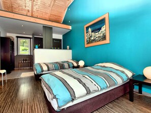 Quarto moderno com uma cama grande, uma pintura de paisagem urbana e vista para uma varanda.