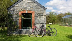 Un bâtiment en pierre, doté d’une arche en briques et d’une fenêtre, entouré d’herbe et d’arbres.