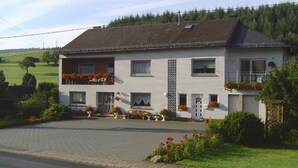 A two-story building with a balcony, a small front porch, and flower boxes. - Unterkunft mit Zwei Baeder in Lirstal (Lirstal)