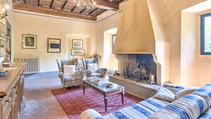 Una sala de estar acogedora con chimenea, vigas de madera en el techo y un tapete estampado.