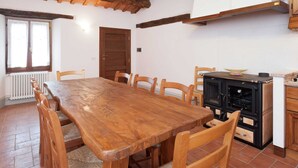 Un comedor con una mesa y sillas de madera, una cocina con estufa y un ventanal con cortinas.