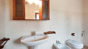 Un baño con un armario de madera, un lavabo, un inodoro y un bidé.