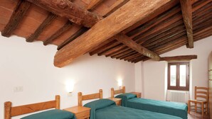 Una habitación con dos camas de madera, una silla de madera y una ventana con vistas.