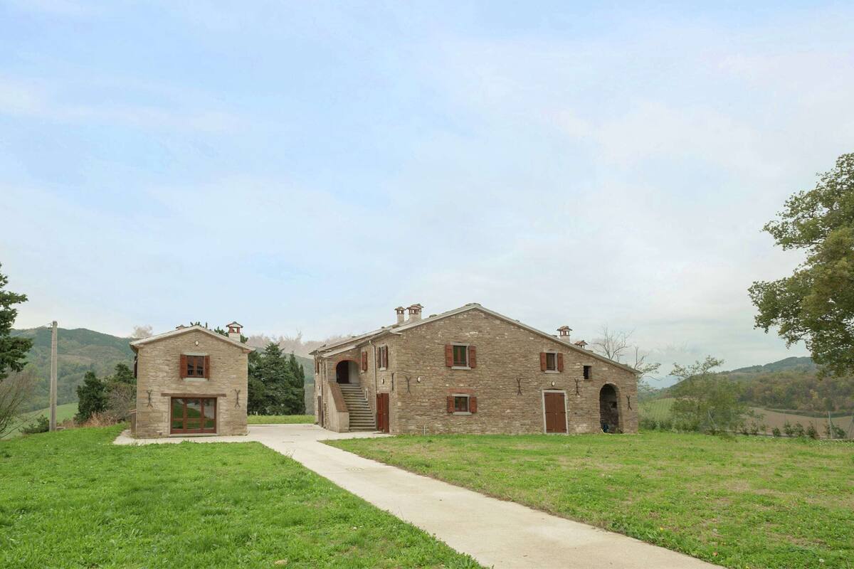 Casa de campo de piedra con una entrada central y dos edificios más pequeños a cada lado.