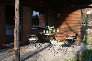 A wooden cabin with a dining table and chairs, a window, and a statue on the wall. - Dog-friendly Holiday Home in the Knull (Neuenstein)