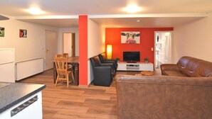 A compact living space with a dining area, a sofa, a TV, and a red accent wall.