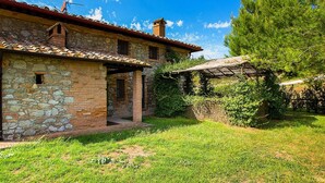 A rustic stone house with a tiled roof, a chimney, and a small porch. - Belvilla by OYO La Provincia (Montecatini Val di Cecina)
