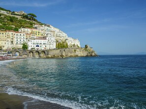 Une ville côtière dotée de bâtiments historiques, d’un pont en pierre et d’une plage.