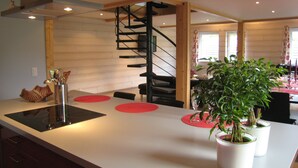 A modern kitchen with a central island, a built-in stove, and a spiral staircase. - Rustic Retreat, Ovifat (Waimes)