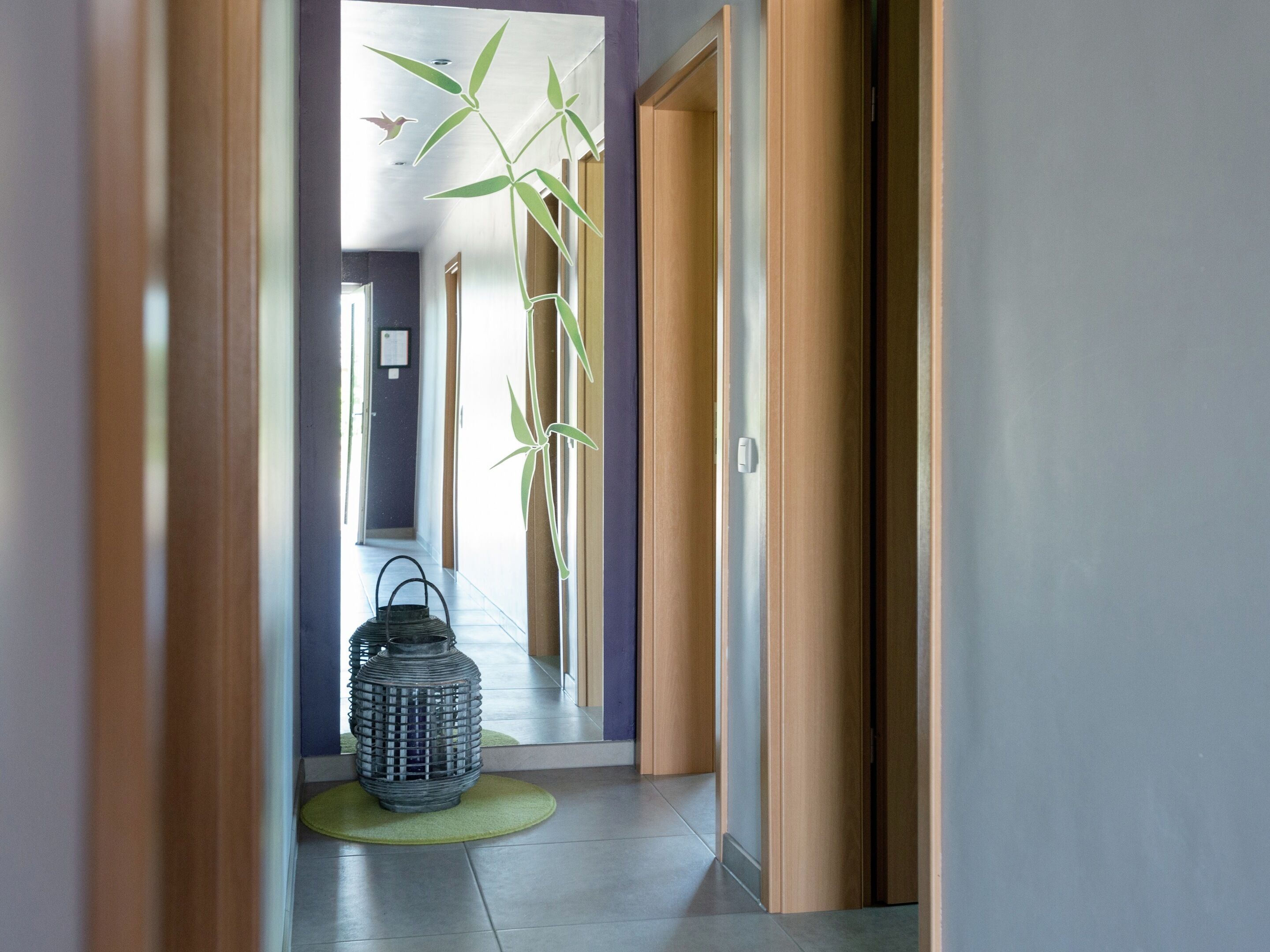 A hallway with bamboo decorations, a lantern, and a green mat.
