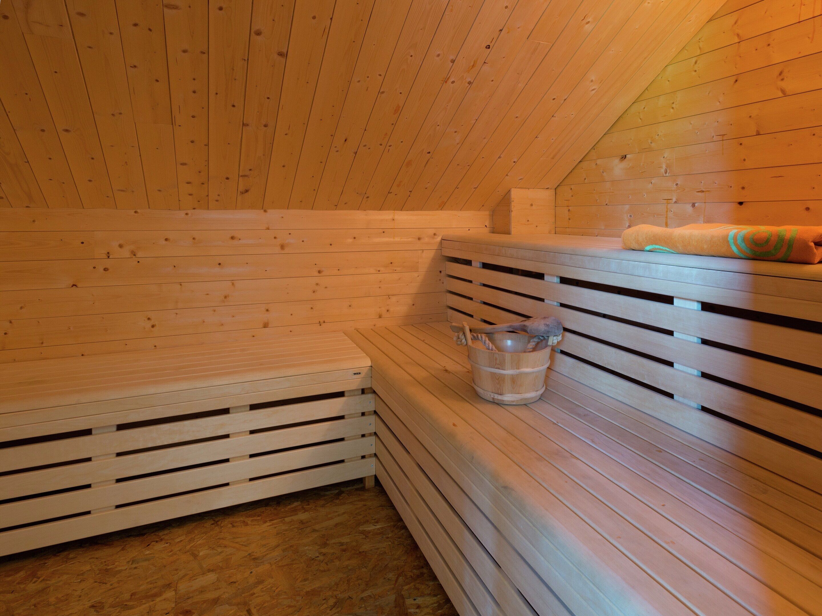 A sauna with wooden benches and a wooden bucket with a towel.