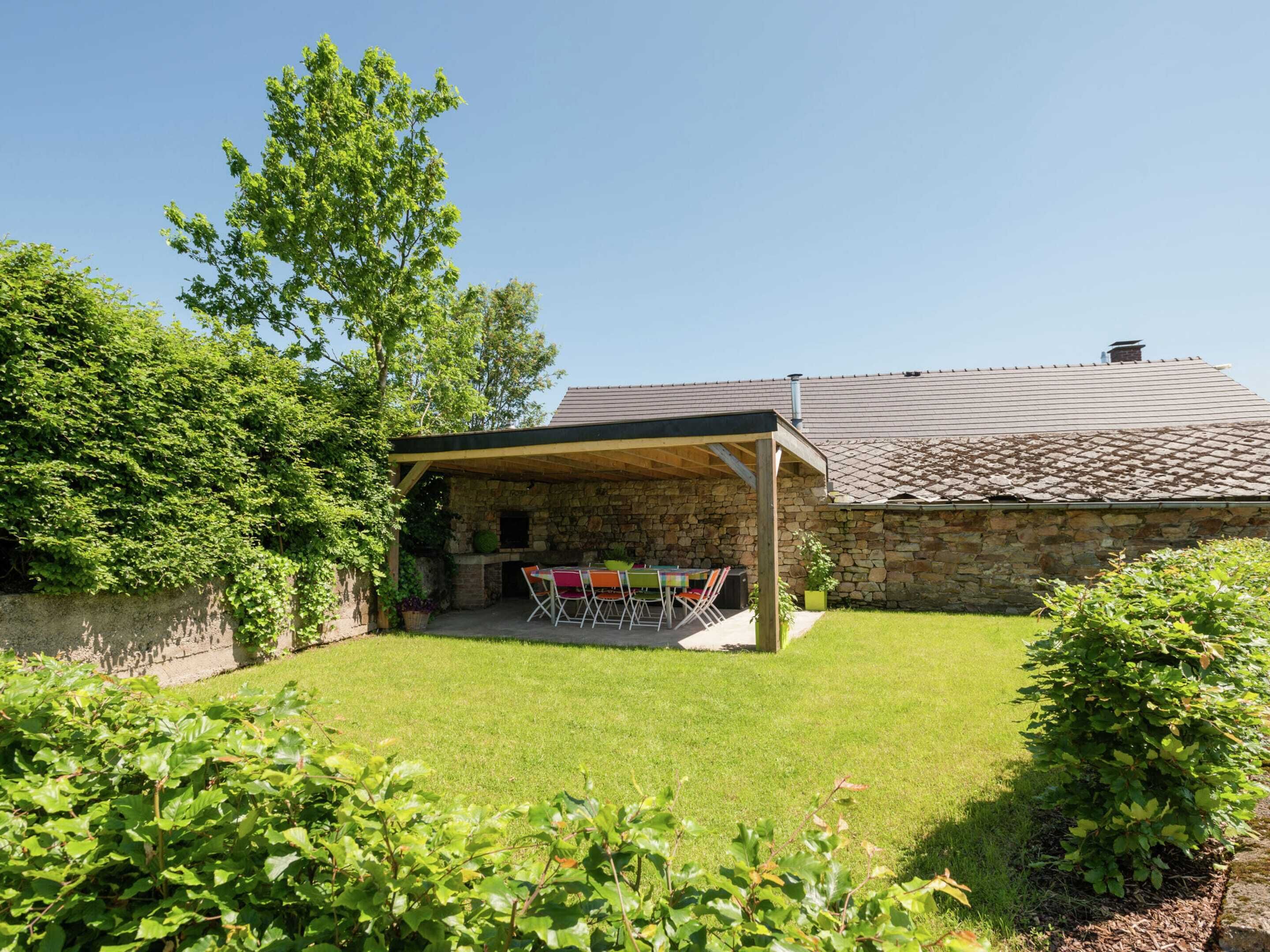A stone house with a covered patio and a barbecue area.