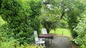 A garden patio with a table and chairs, surrounded by dense foliage. - Ferienhaus in Homberg (Homberg)