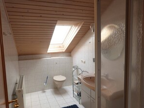 Une petite salle de bain compacte, dotée d’un puits de lumière, de toilettes, d’un lavabo et d’un espace douche.