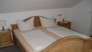Un lit double avec deux oreillers, une t ête de lit en bois et deux tables de chevet avec des lampes.