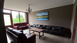 A living room with a red sofa, a black sofa, a wooden coffee table, and a chandelier.