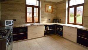 A modern kitchen with a stove, microwave, and large windows.