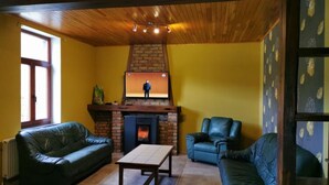 A living room with a brick fireplace, leather sofas, and a wooden ceiling.