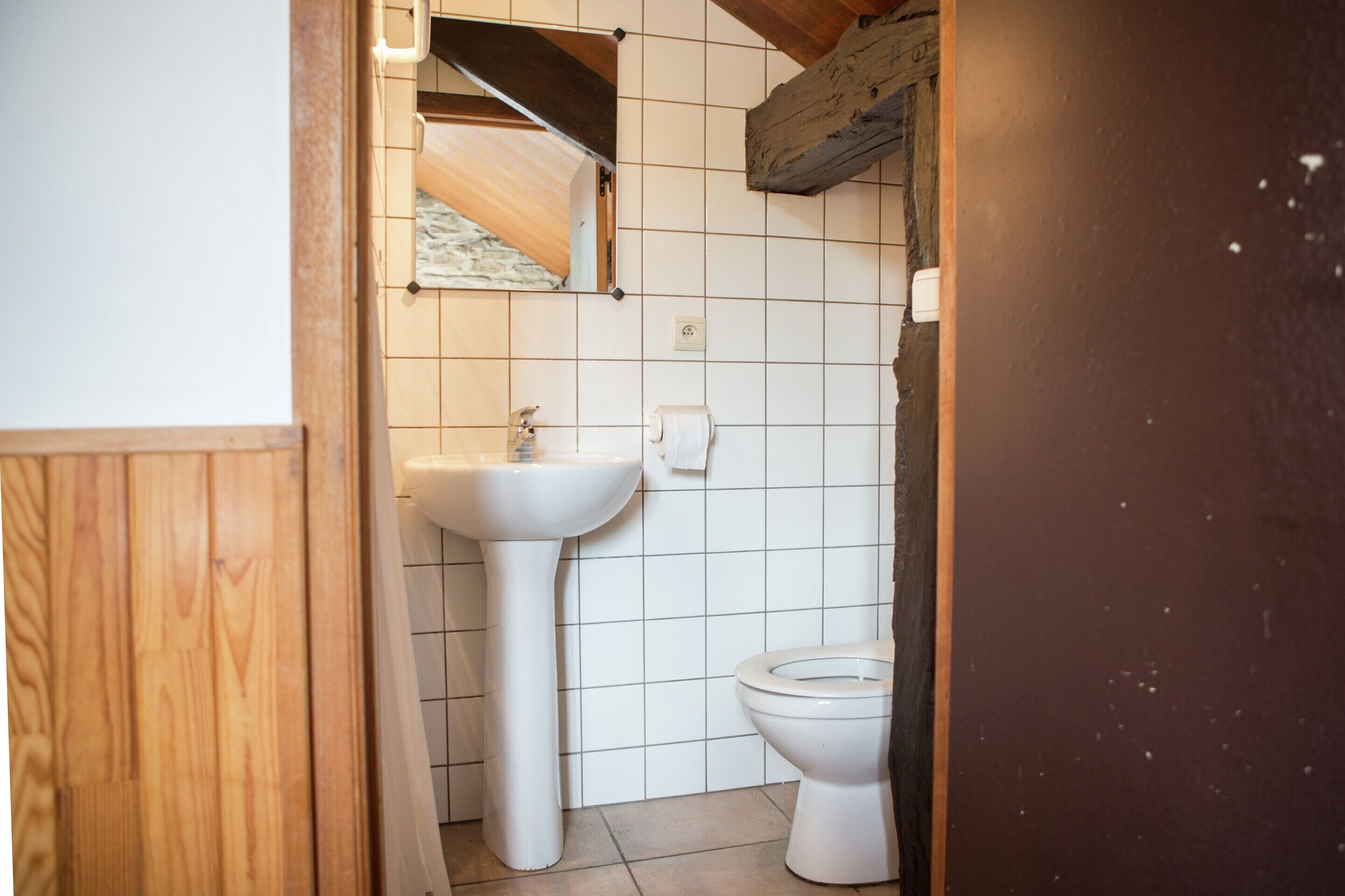 Un baño pequeño con un lavabo blanco, inodoro y paredes con azulejos.