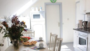 A dining area with a table set for two, a vase of flowers, and a watermelon on the table.