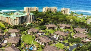 A resort with multiple bungalow-style buildings, a central swimming pool, and a view of the ocean.