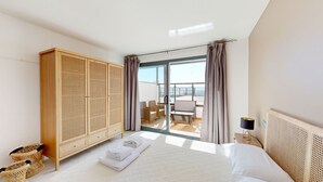 A bedroom with a bed, a wardrobe, a balcony with a table and chairs, and a view of the sea. - APTO NAUTICO (Ampolla)