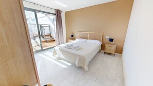 A bedroom with a bed, a nightstand, a lamp, and a view of a balcony. - APTO NAUTICO (Ampolla)