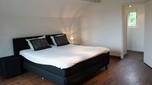 A modern bedroom with a black bed frame, white bedding, and two decorative pillows. - Mansion in Spa Liege With Private Garden (Spa)
