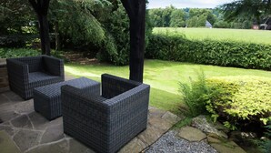 An outdoor seating area with wicker furniture under a pergola, surrounded by a well-maintained garden and a view of the countryside. - Mansion in Spa Liege With Private Garden (Spa)