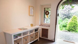 A room with a white console table, wicker baskets, a small window with a wreath, and a view of greenery outside. - Mansion in Spa Liege With Private Garden (Spa)