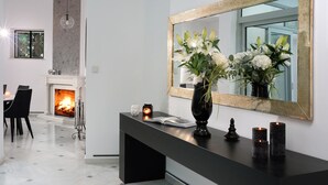 Ein modernes Wohnzimmer mit Kamin, Essbereich und einem großen Spiegel an der Wand.
