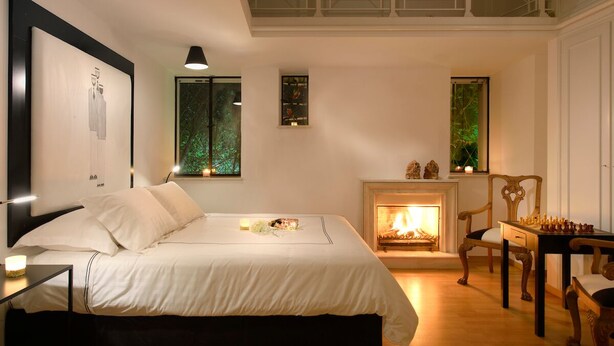 Ein Schlafzimmer mit Bett, Kamin, einem Schachbrett und Kunstwerken an den Wänden.