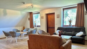 A living room with a brown sofa, wicker chairs, a black leather couch, and a dining table.