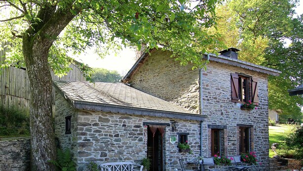 A stone building with a sloped roof, a bench outside, and a dog statue. - Forest Hideaway, Baillamont (Bievre)