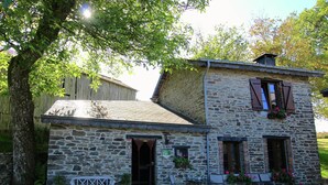 A stone building with a wooden door, a bench, and outdoor seating. - Forest Hideaway, Baillamont (Bievre)