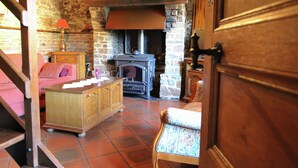 A rustic room with a stone wall, a fireplace, a wooden cabinet, a chair, and a bed. - Forest Hideaway, Baillamont (Bievre)