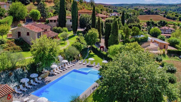 A pool area with lounge chairs and umbrellas, surrounded by greenery and buildings. - Farmhouse Umbria-tuscany With Pool (Citta della Pieve)