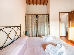 A bedroom with a bed, a nightstand, a lamp, and a window with curtains.