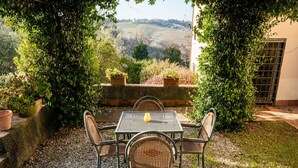 A patio with a table and chairs, surrounded by greenery and a view of hills. - Apartment With Swimming Pool in San Casciano (San Casciano in Val di Pesa)
