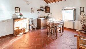 A rustic kitchen with wooden beams, a tiled floor, and a dining area with chairs and a table. - Apartment With Swimming Pool in San Casciano (San Casciano in Val di Pesa)