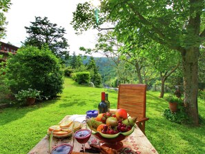 Un'apparecchiatura per un picnic su un prato verde, con un tavolo apparecchiato per un pasto, che include frutta, pane e una bottiglia di vino.