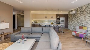 A modern living room with a sectional sofa, a coffee table, and a colorful chair. - Nastazia Luxury Beach House (Ialisos)