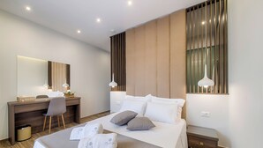 A modern hotel room with a large bed, a desk, and a mirror. - Nastazia Luxury Beach House (Ialisos)